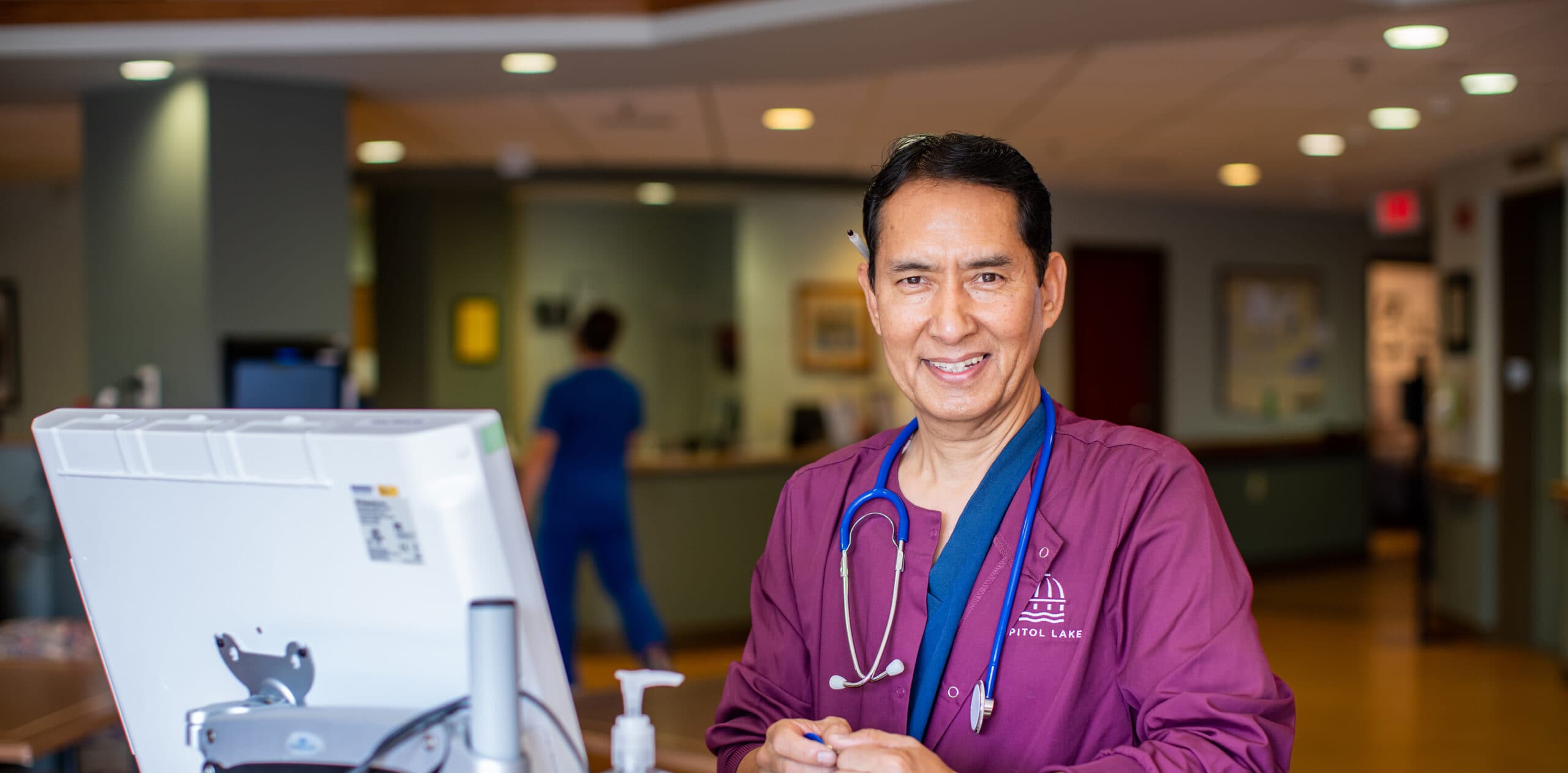 A Capitol Lakes healthcare worker stands at a desk.